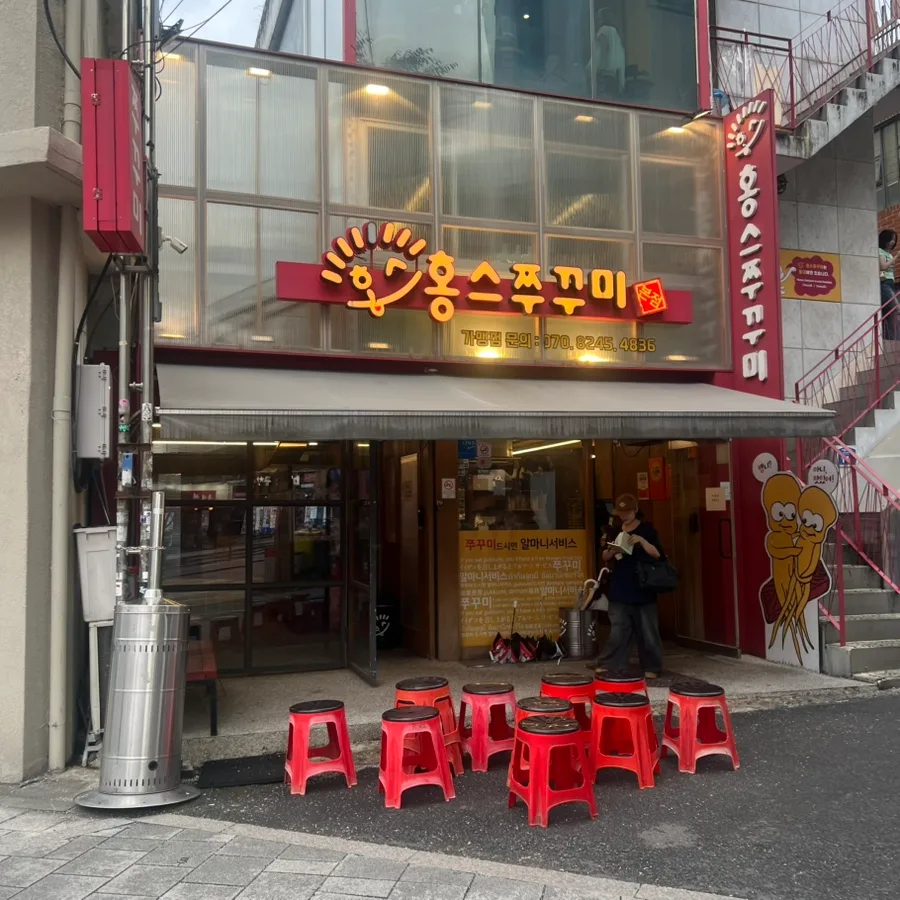 ホンスチュクミ 弘大本店 — 赤い腰掛けが並ぶ店先