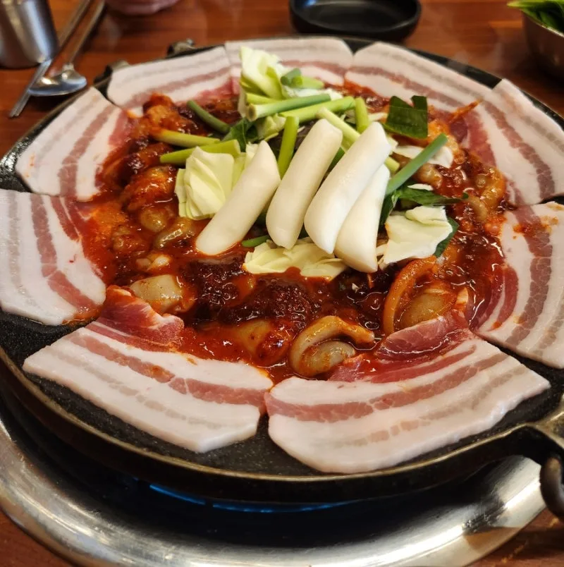 イイダコのまわりに豚バラ肉を並べた鉄板