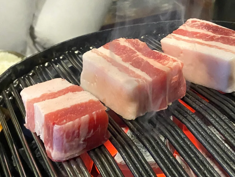 炉の網にのせた厚切りのサムギョプサル