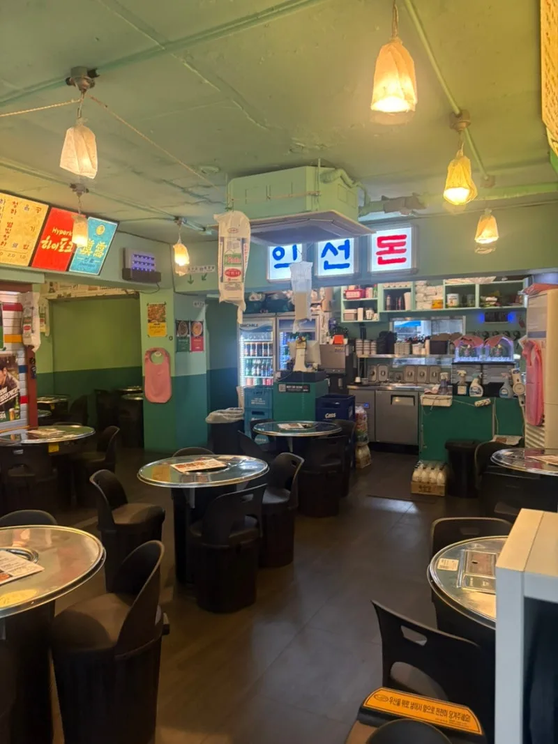 益善ドン 本店 — 緑の壁と丸テーブルの客席