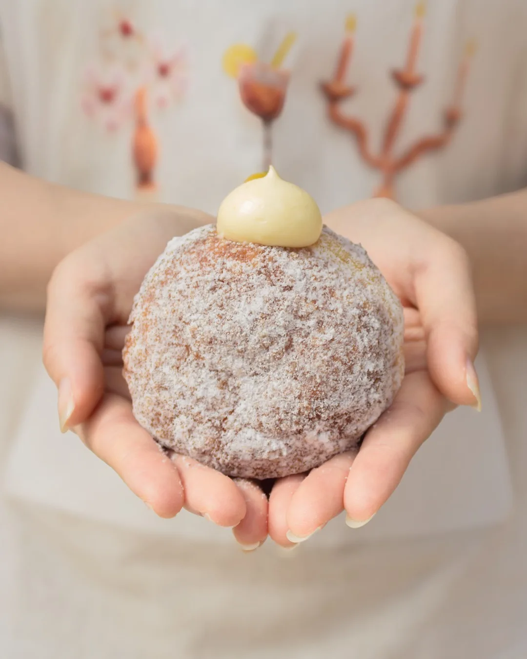I’m donut? 聖水店 — 両手に載せた粉糖の丸いドーナツ