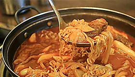 赤いスープの鍋と持ち上げた麺