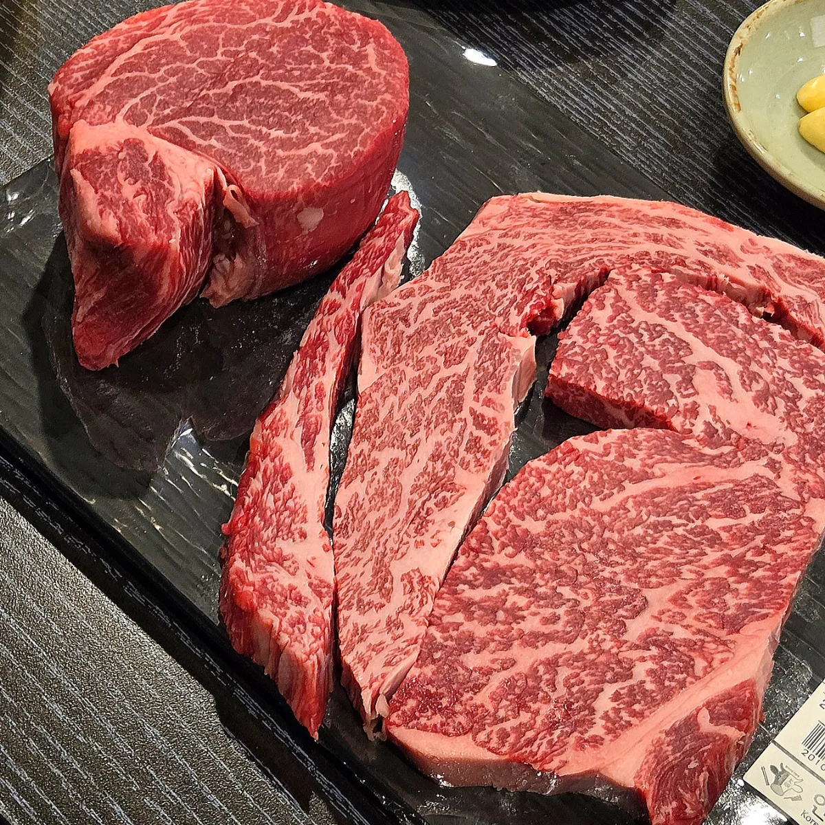 人生韓牛 — 黒皿に並ぶ厚切り霜降り肉