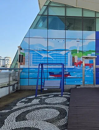海の壁画前に置かれたブランコ