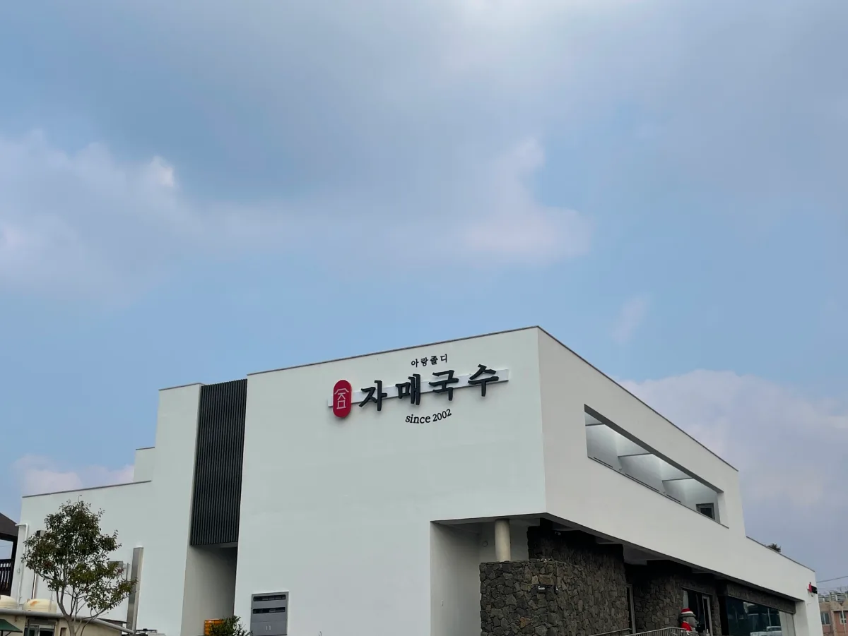 姉妹ククス 本店 — 青空に映える白壁の店舗