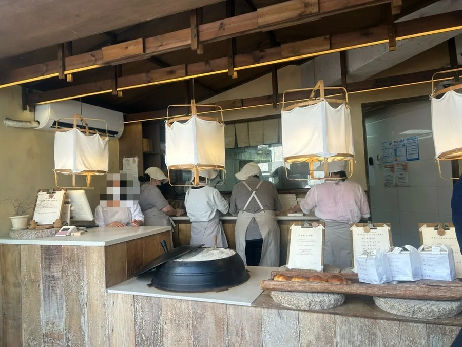 ジャヨンド塩パン 聖水店 — 木造カウンターで働くスタッフ