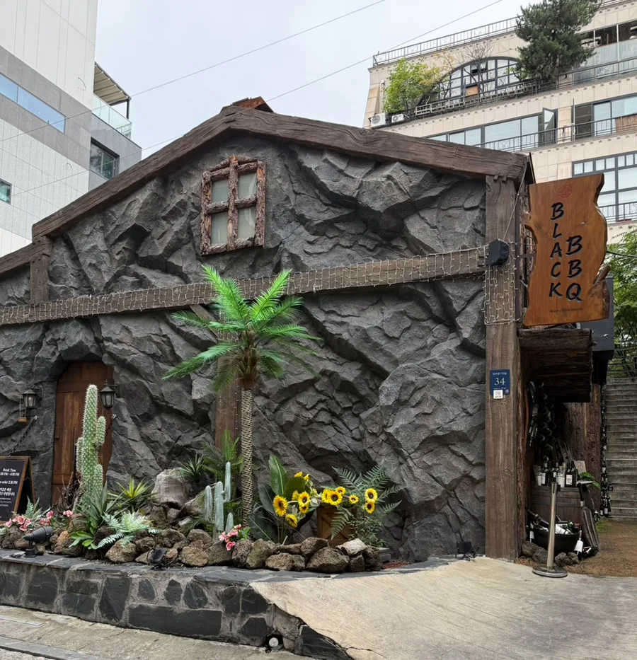 黒い岩壁と木製看板の店舗