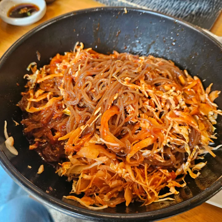 黒い器の赤い麺と野菜