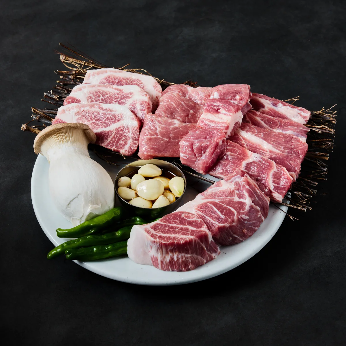 直火匠人 新堂本店 — 皿に盛られた生の豚肉と野菜