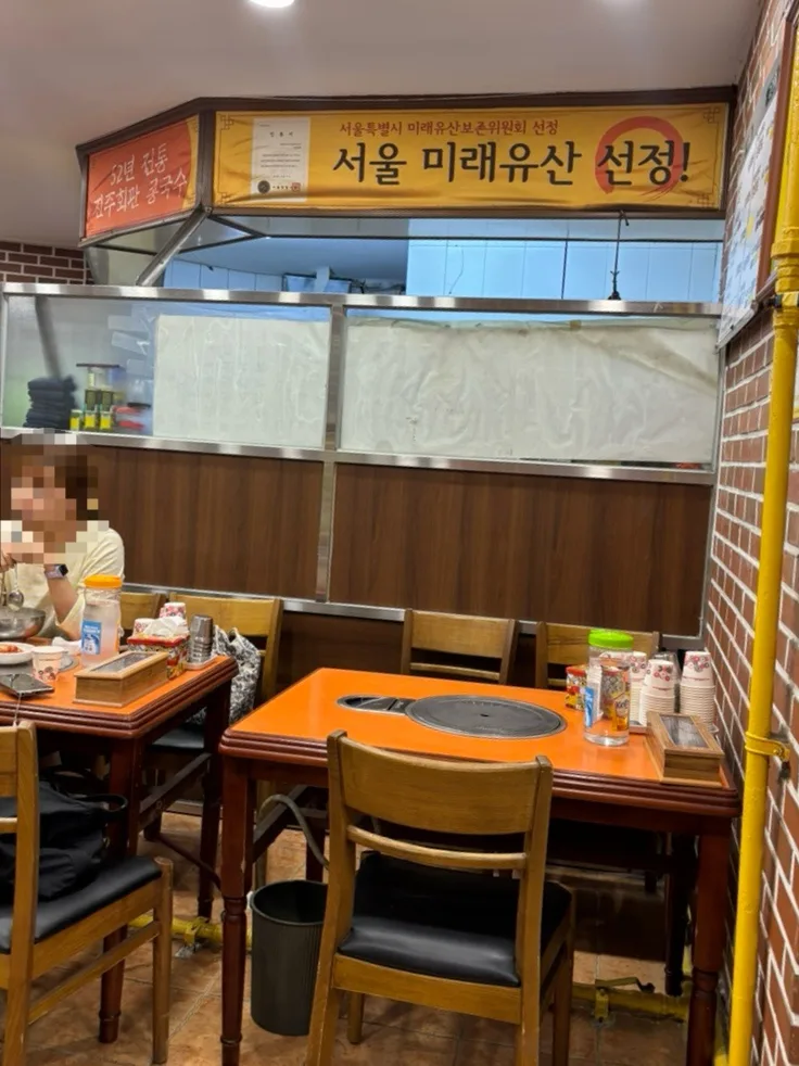 晋州会館 — オレンジ卓と厨房前の客席