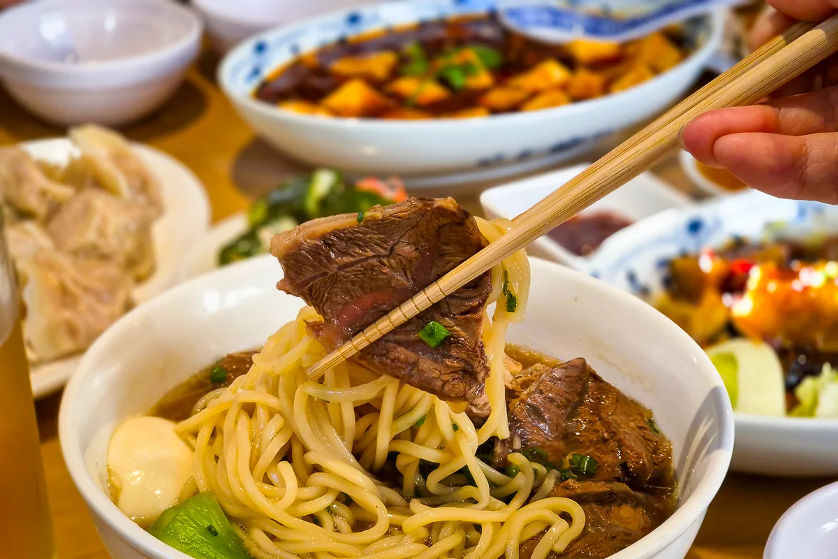 ジンジュン牛肉麺館 本店 — 箸で持ち上げた牛肉と麺