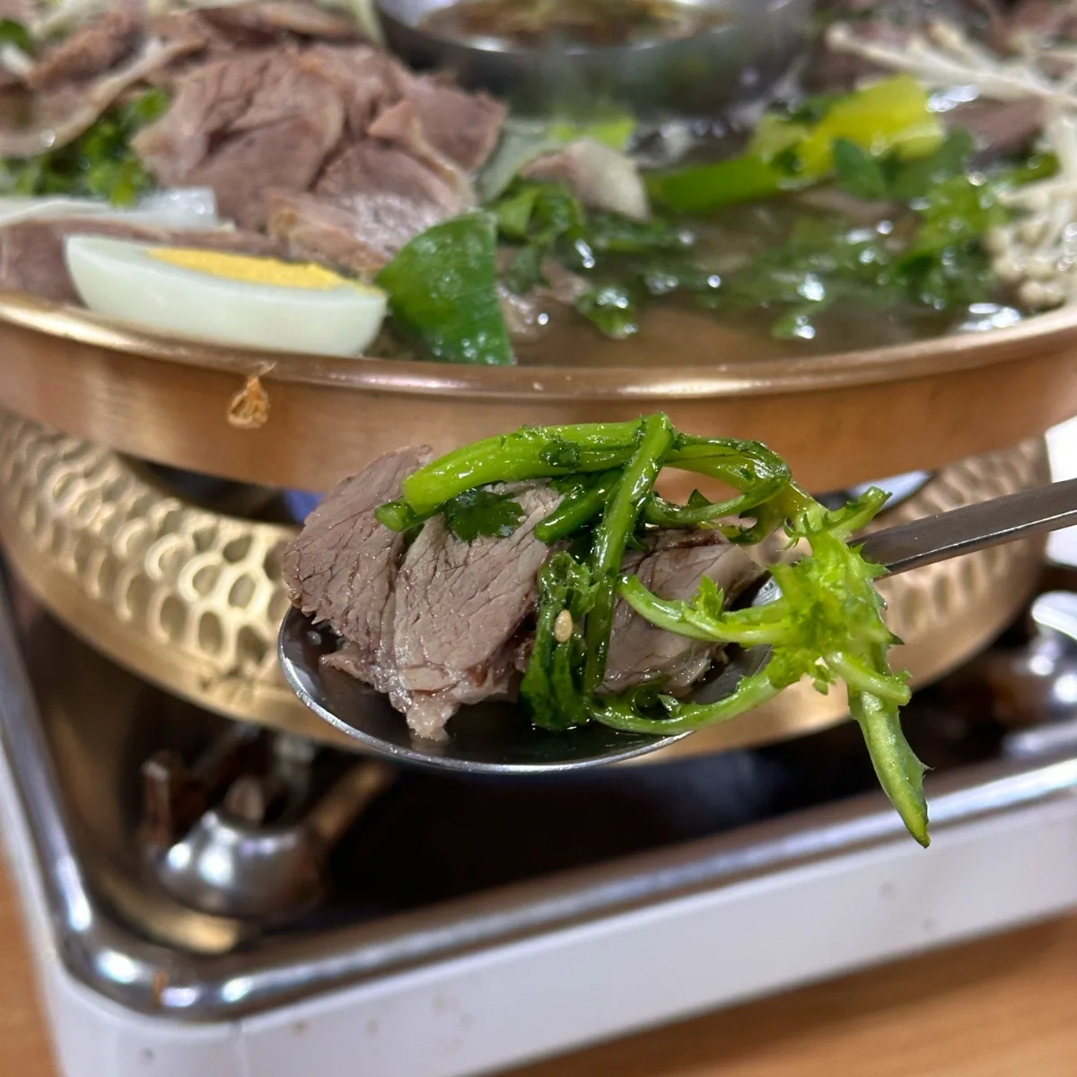 真味平壌冷麺 — 春菊と牛肉を載せたスプーン