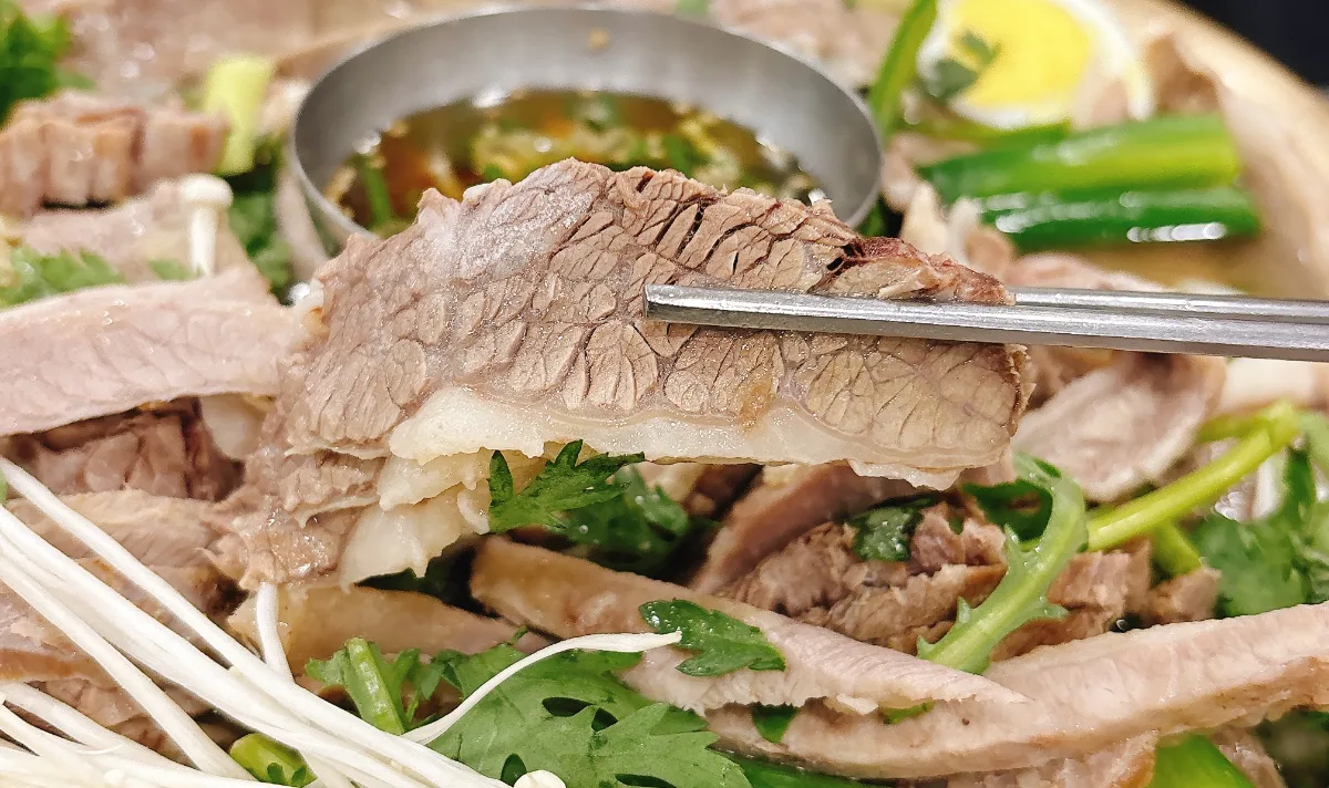 真味平壌冷麺 — 箸で持ち上げたゆで牛肉