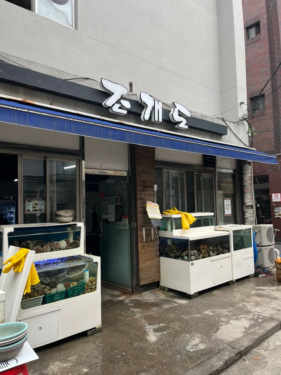 チョゲド — 店名看板と貝の生け簀が並ぶ店先