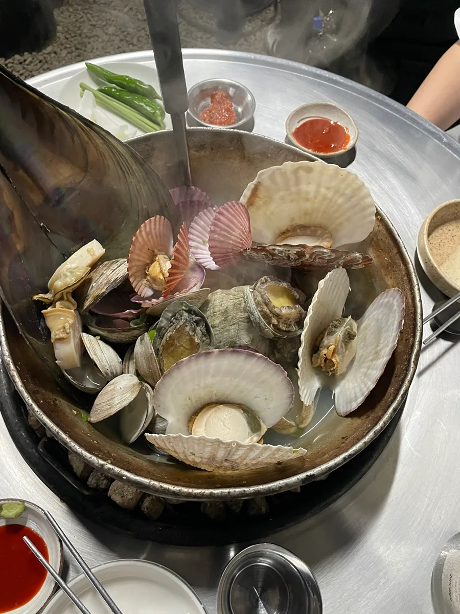 湯気立つ焼き網の上の貝の盛り合わせ