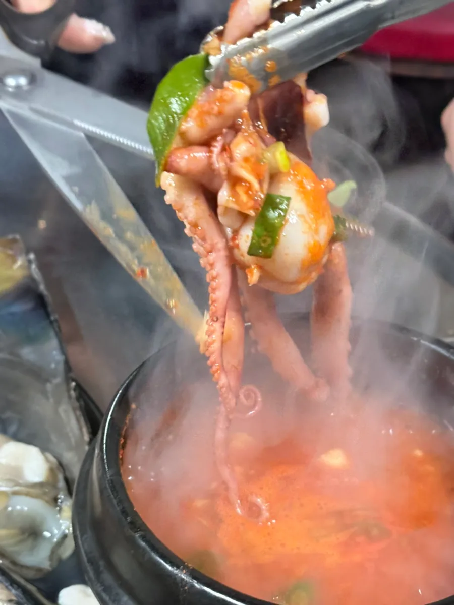 トングで掲げる湯気立つタコ脚