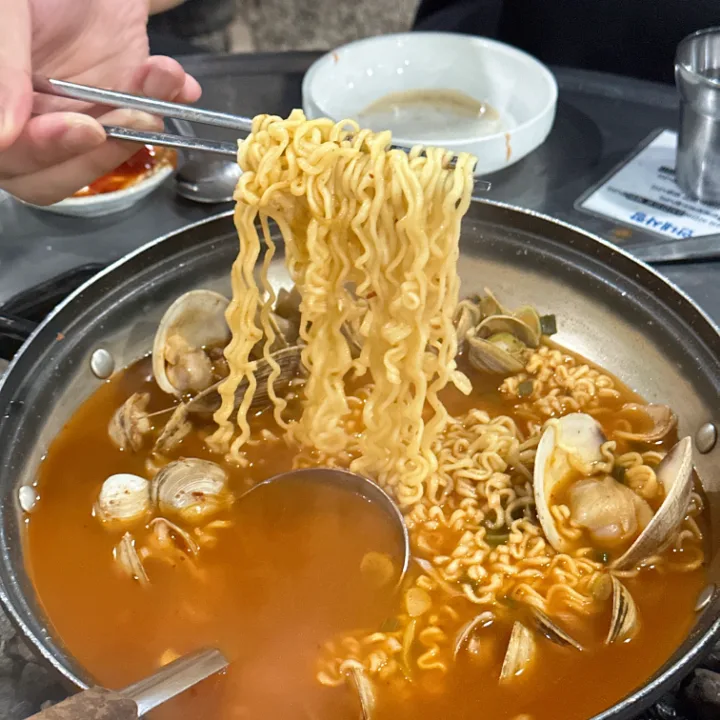 貝入り辛味ラーメンを持ち上げる