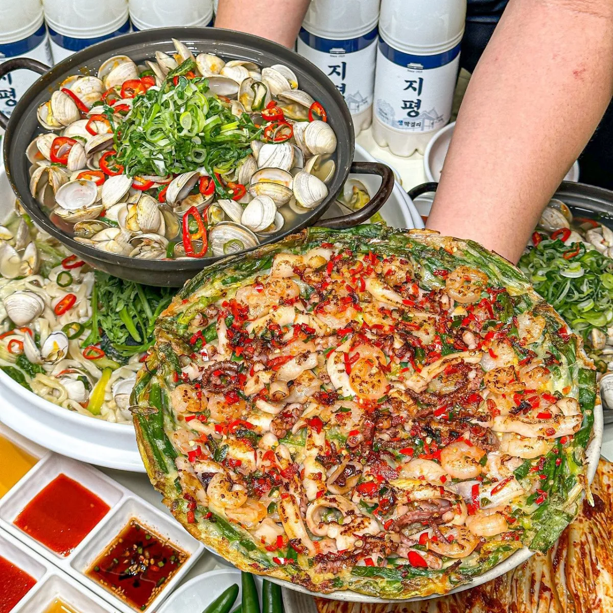 ジョジョカルグクス 聖水店 — 海鮮チヂミとアサリ鍋が並ぶ食卓