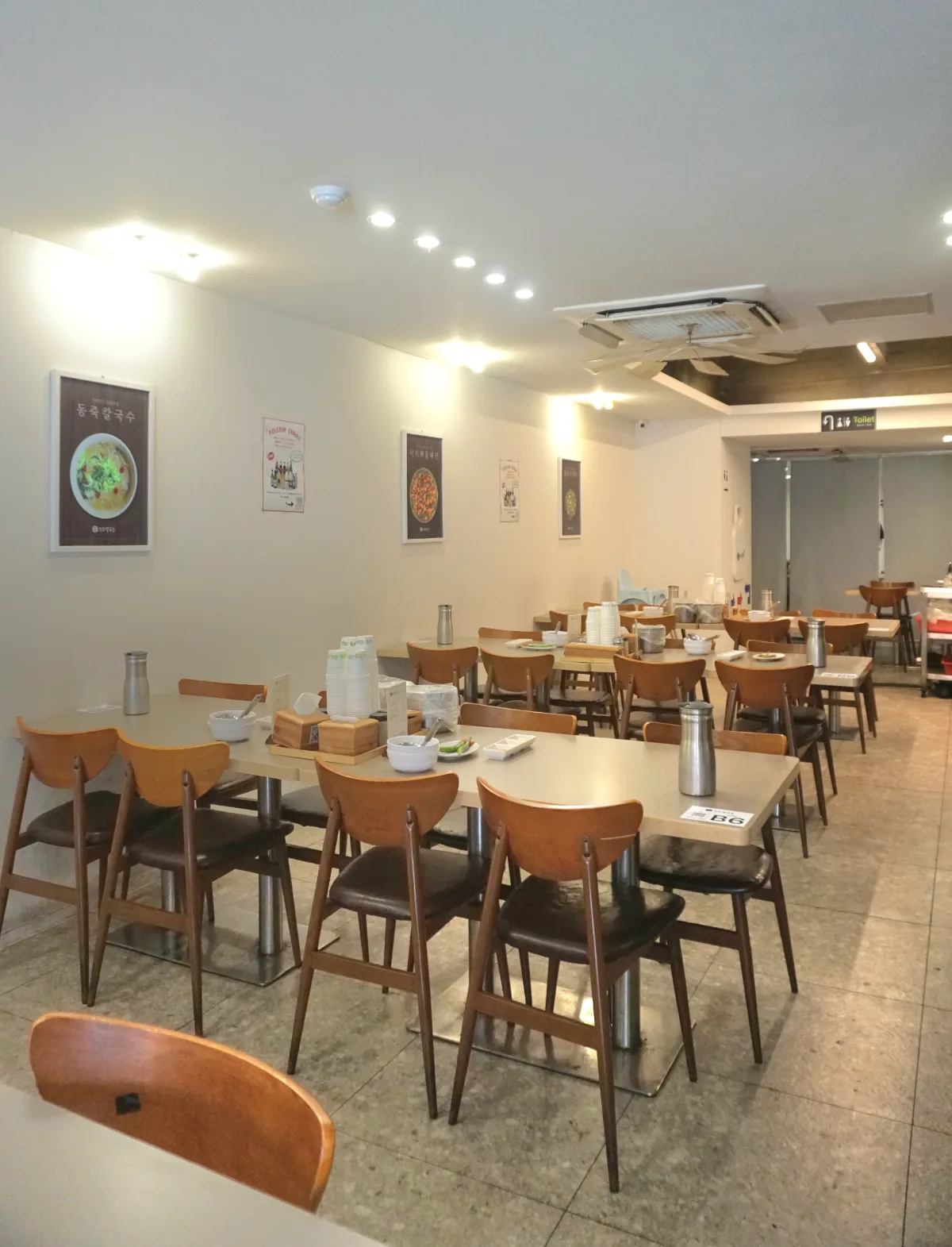 ジョジョカルグクス 市庁店 — メニュー写真が並ぶ壁と長いテーブル列