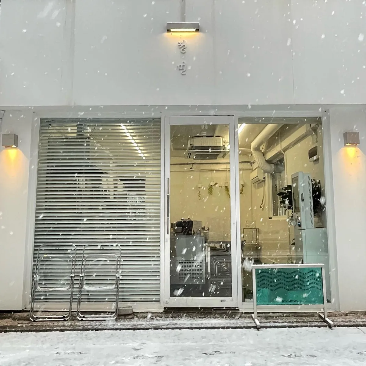 情麺 — 雪が舞う白い店舗と正面の看板