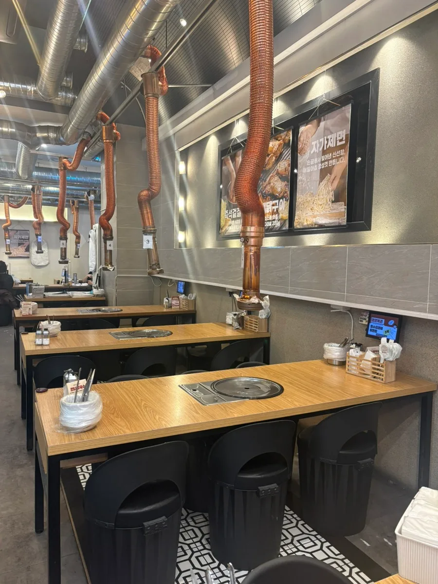 排煙管が続く木製テーブル席