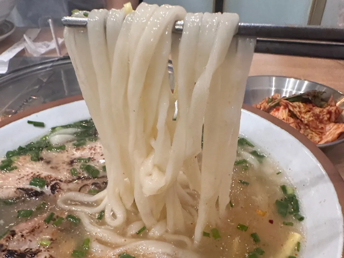 箸で持ち上げた太麺と鶏スープ