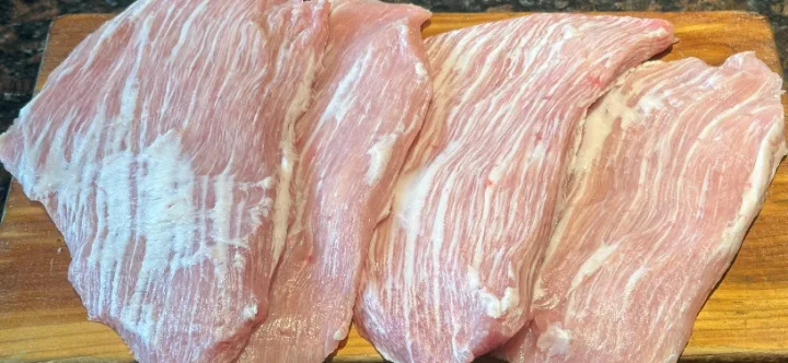 木のまな板に並ぶ厚切り肉