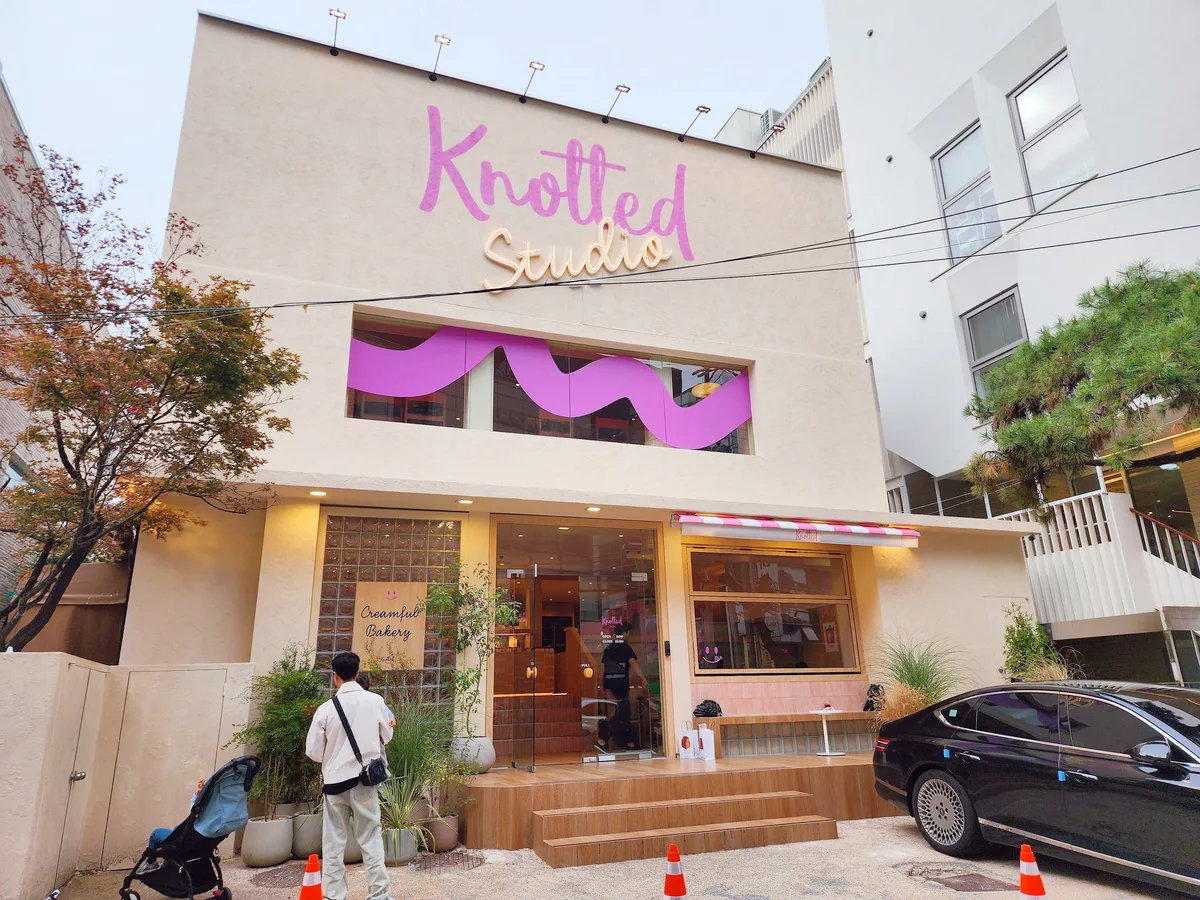ノティッド・スタジオ 清潭店 — 木々と車の前に立つ白い店舗