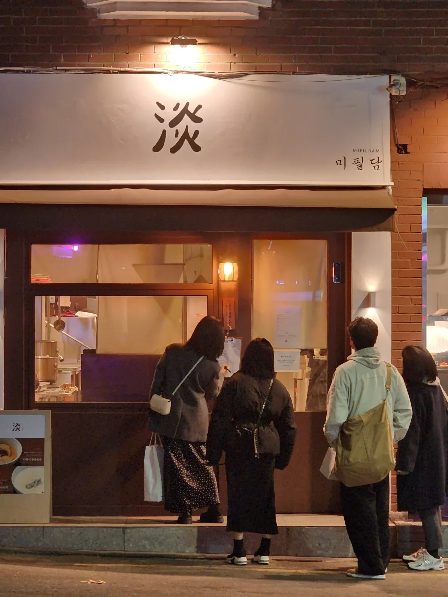 「淡」の看板の下で順番を待つ人たち