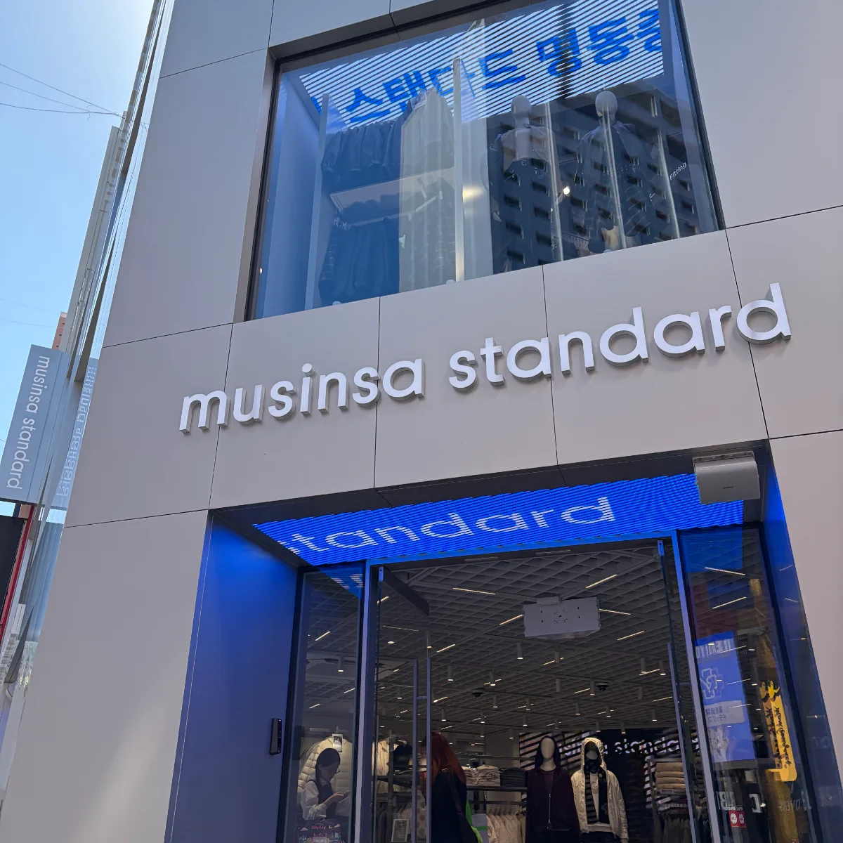 MUSINSA STANDARD 明洞店 — 青い照明と店舗正面の看板