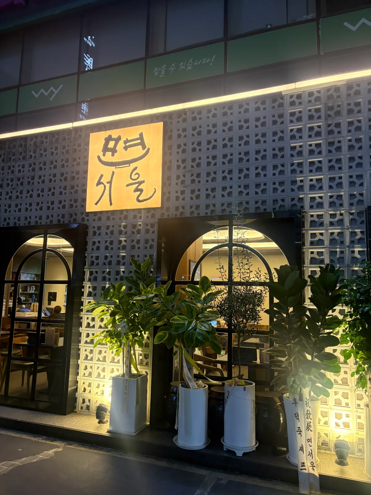 灯りに浮かぶ店名看板と植栽