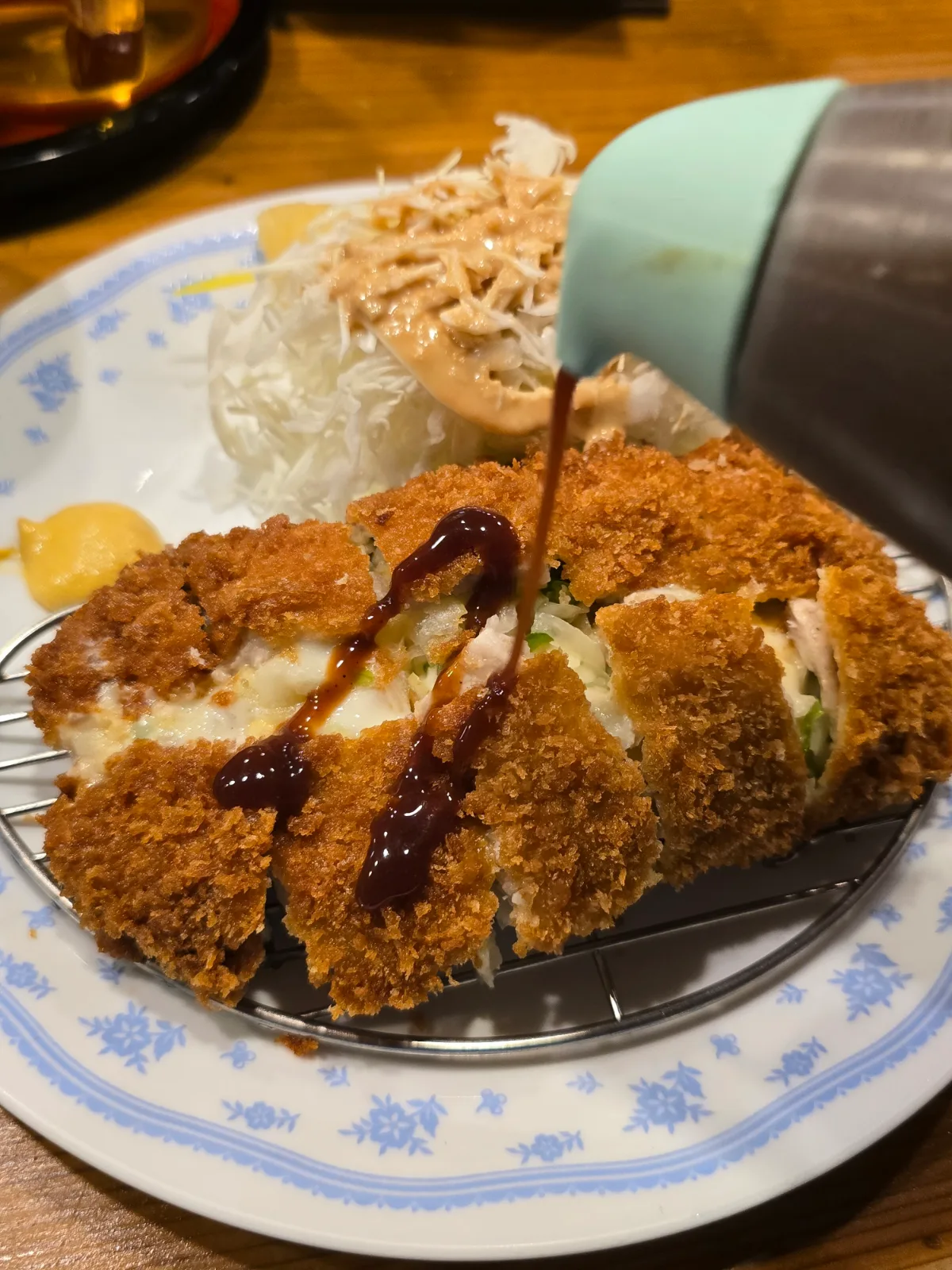ソースを注ぐチーズ入りカツ