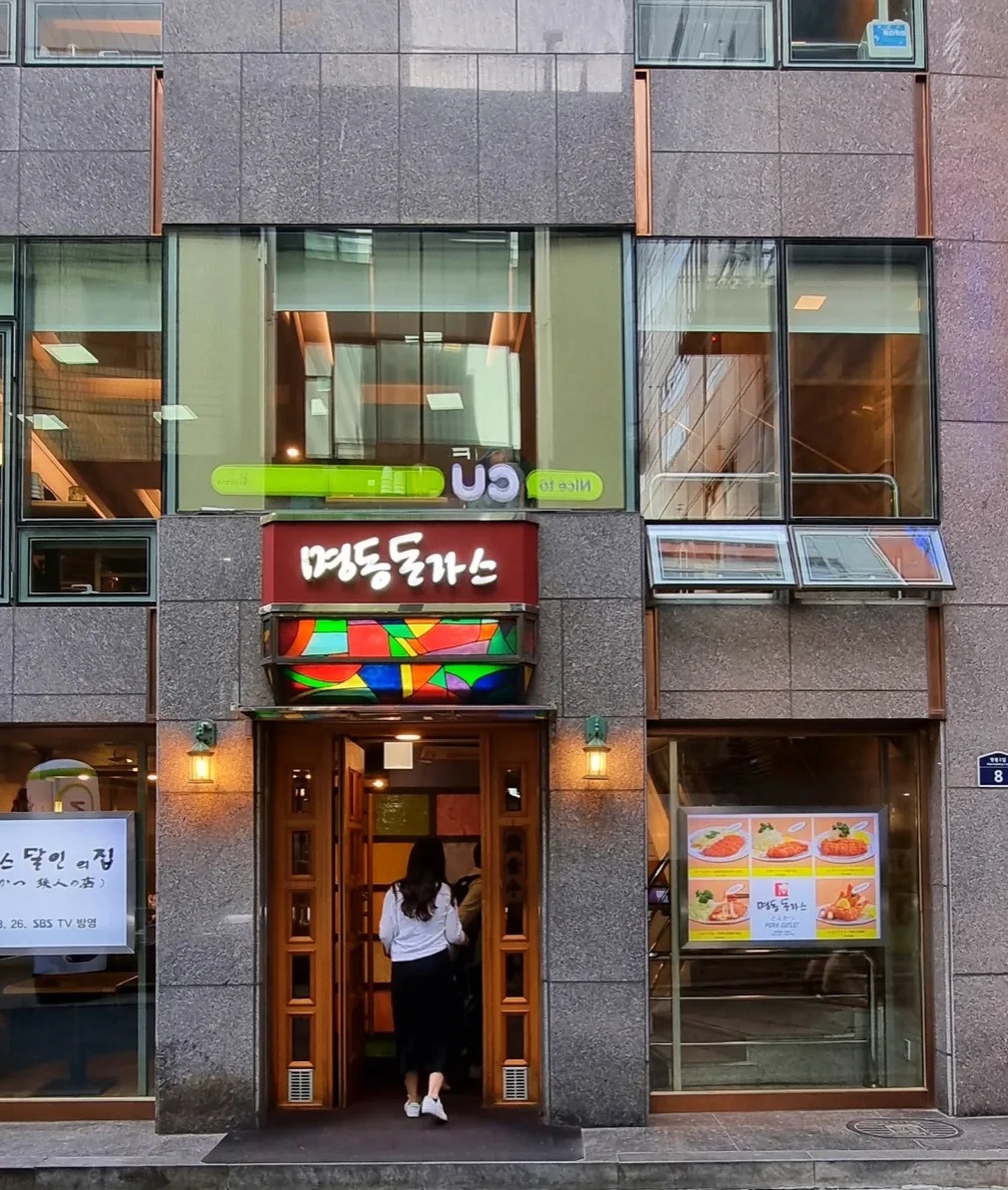 明洞トンカツ — 彩色ガラスの庇と店名看板