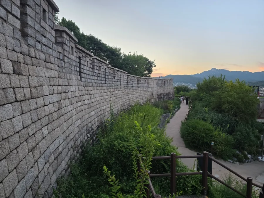 駱山公園 — 城壁沿いの緑道と夕焼けの山