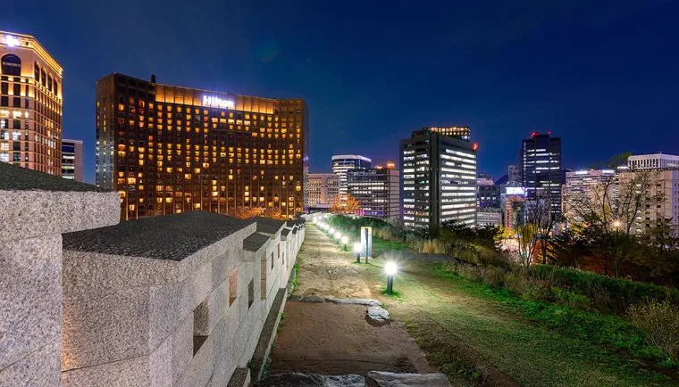 夜の城壁沿いの道と都心のビル