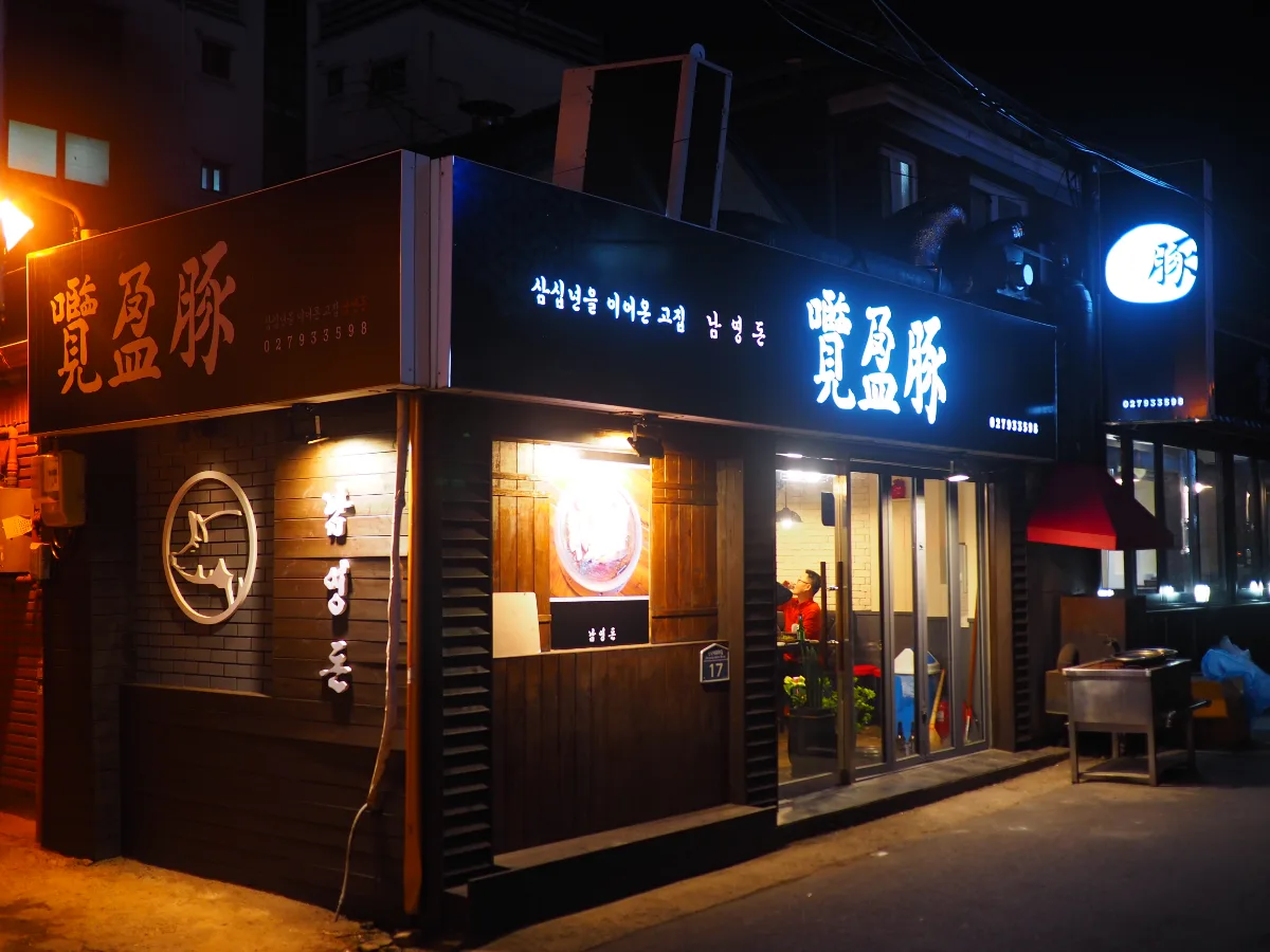 覧盈豚 本店 — 夜に光る「覽盈豚」の看板と入口