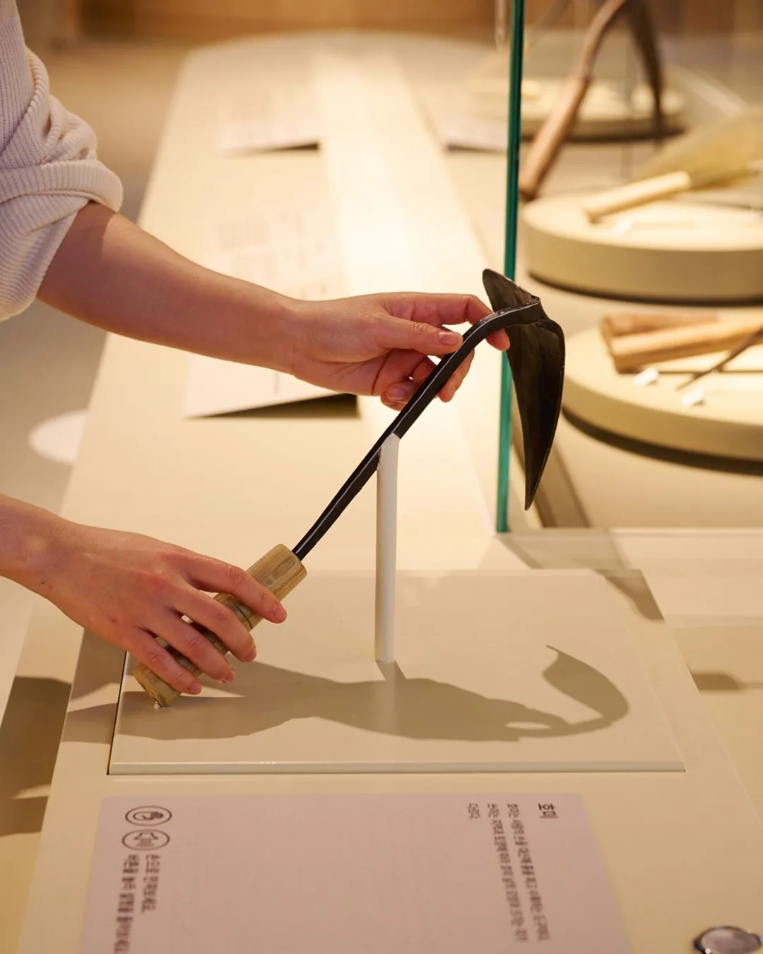 展示された農具に触れる手
