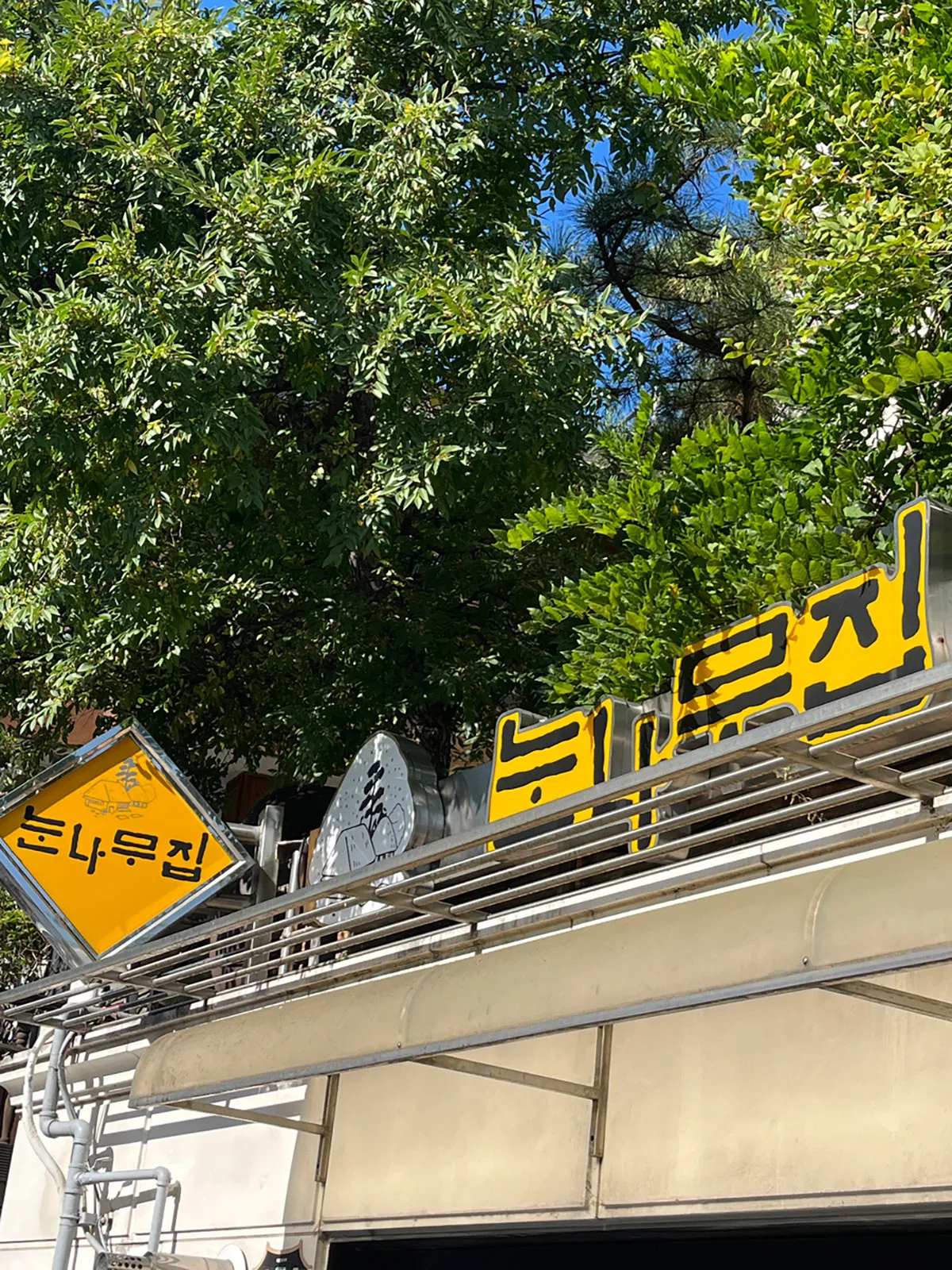 木々を背にした黄色い店名看板