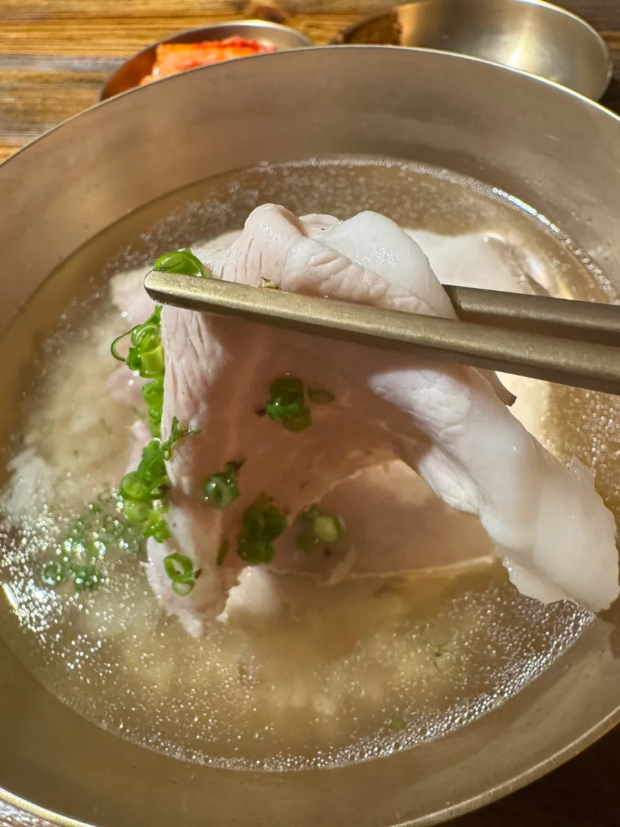 箸で持ち上げる茹で豚肉とスープ