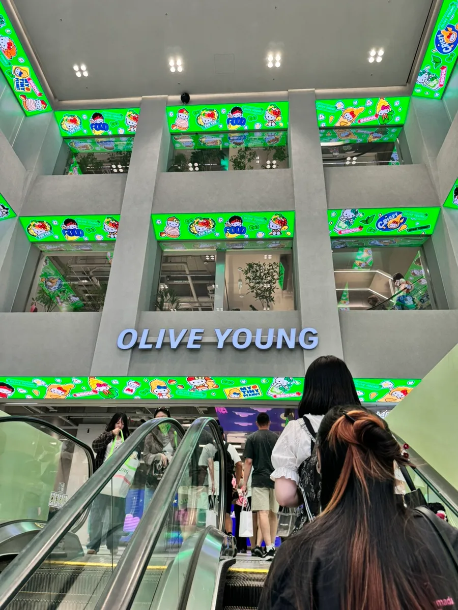 OLIVE YOUNG 明洞タウン店 — 吹き抜けを上るエスカレーター