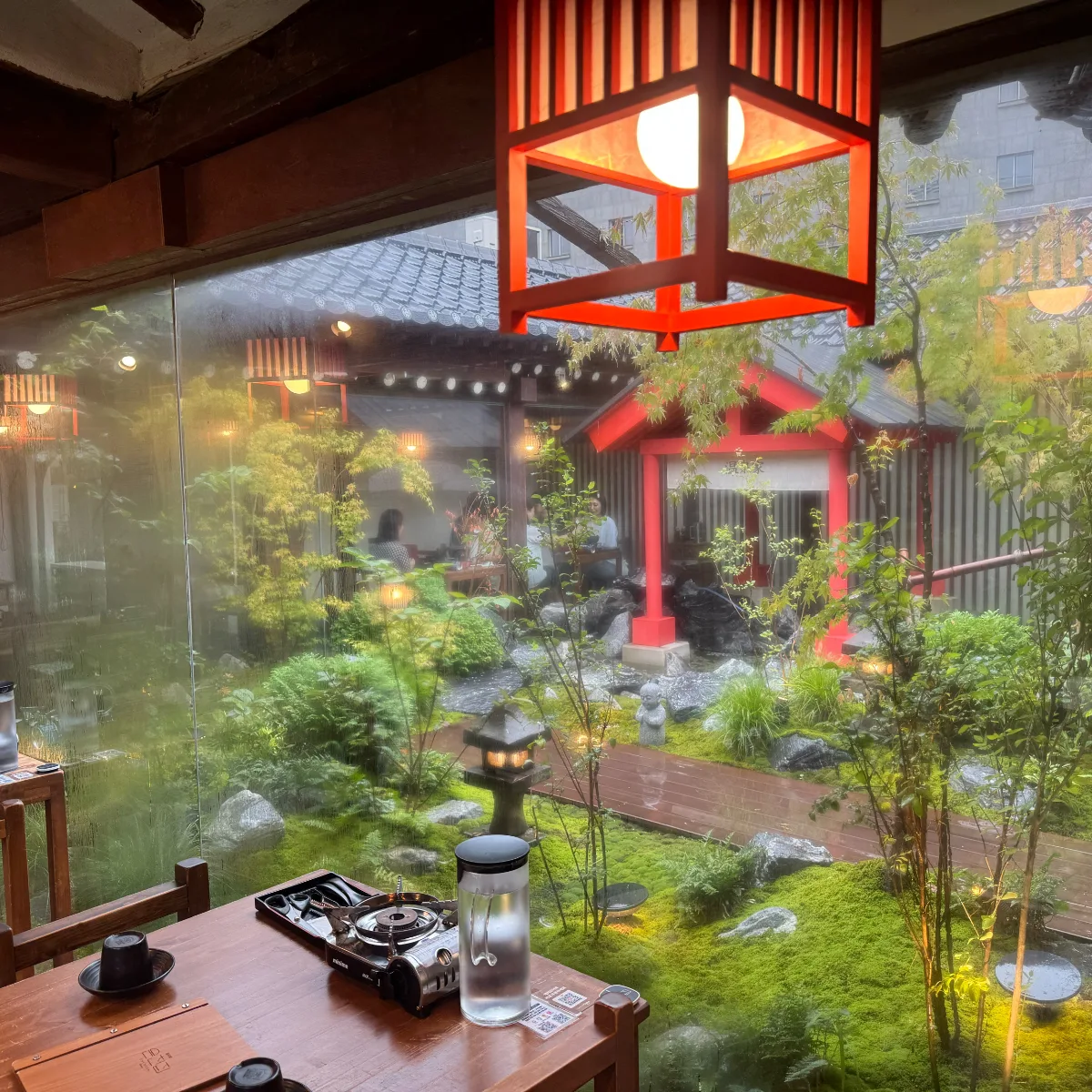 赤い灯籠越しに望む苔庭