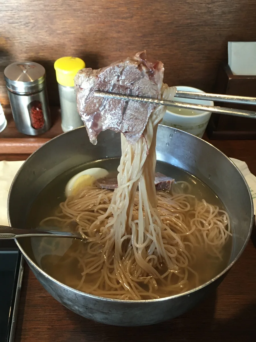 箸で持ち上げた冷麺と牛肉