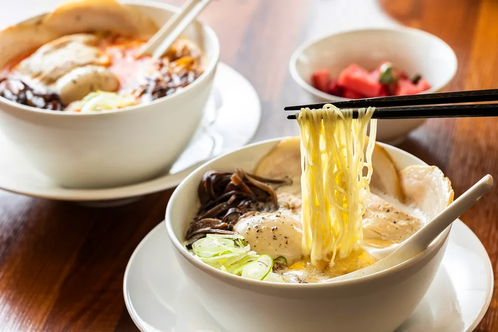 俺のラーメン 本店 — 箸で持ち上げた白湯ラーメン
