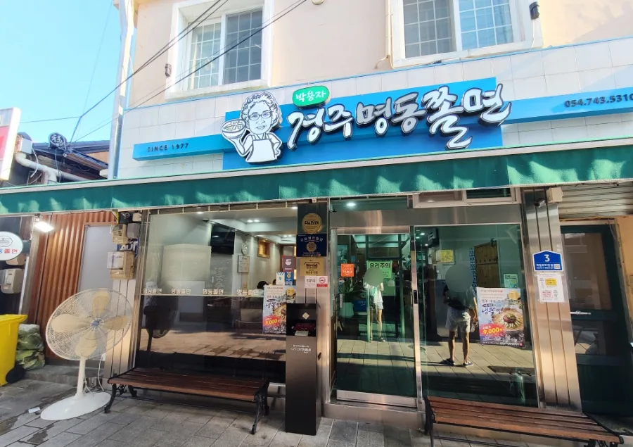 パク・ヨンジャ慶州明洞チョルミョン 本店 — 青い看板とガラス扉の店先