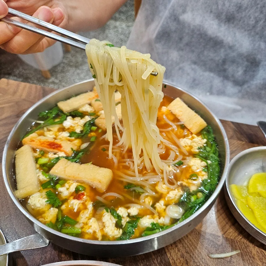 油揚げをのせた麺を箸で持ち上げる