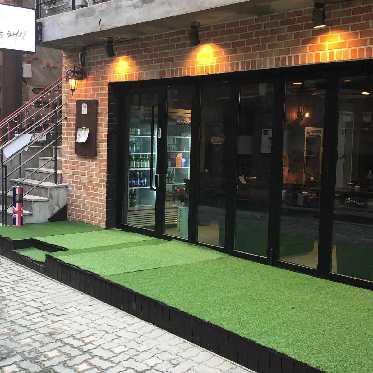 プルトゥンヌンテジ — レンガ壁と黒いガラス扉の店先