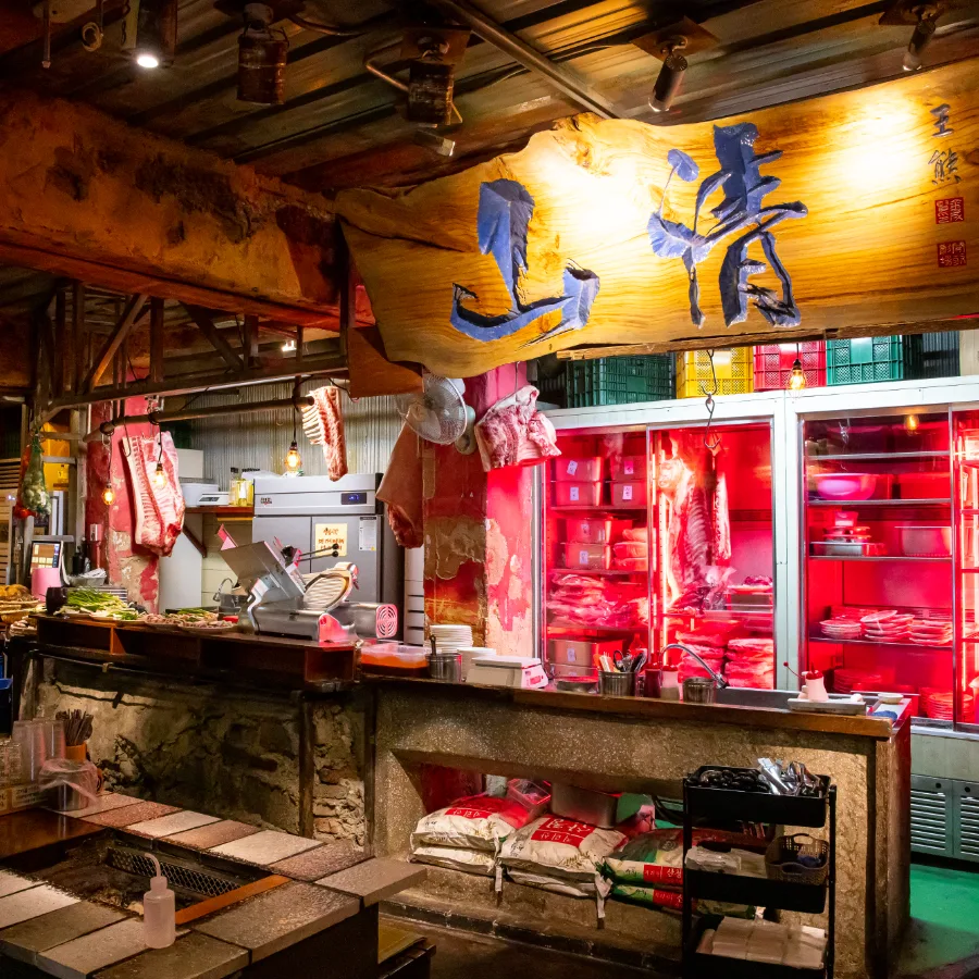 赤い肉ケースと木彫り看板の厨房