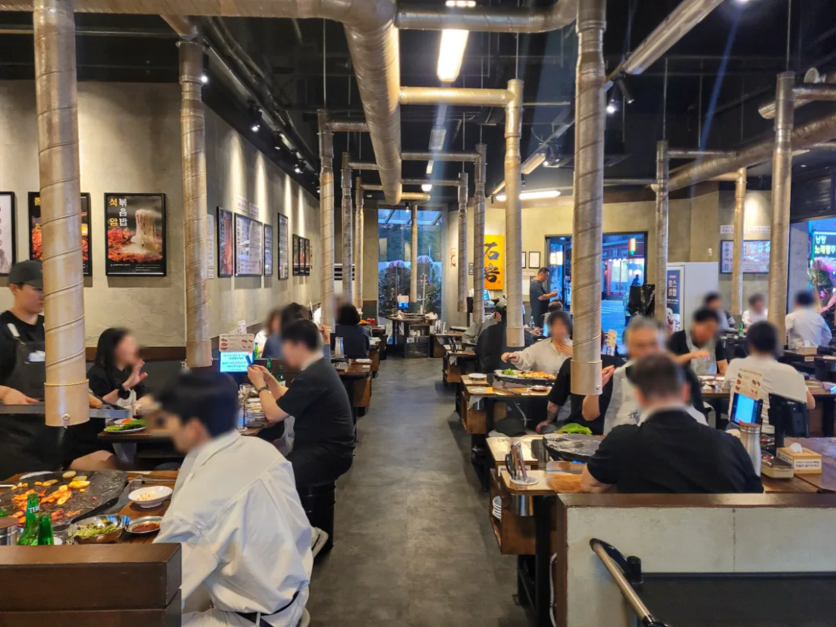 石岩生ソグムグイ 龍山店 — 銀色の配管が伸びる賑わう店内