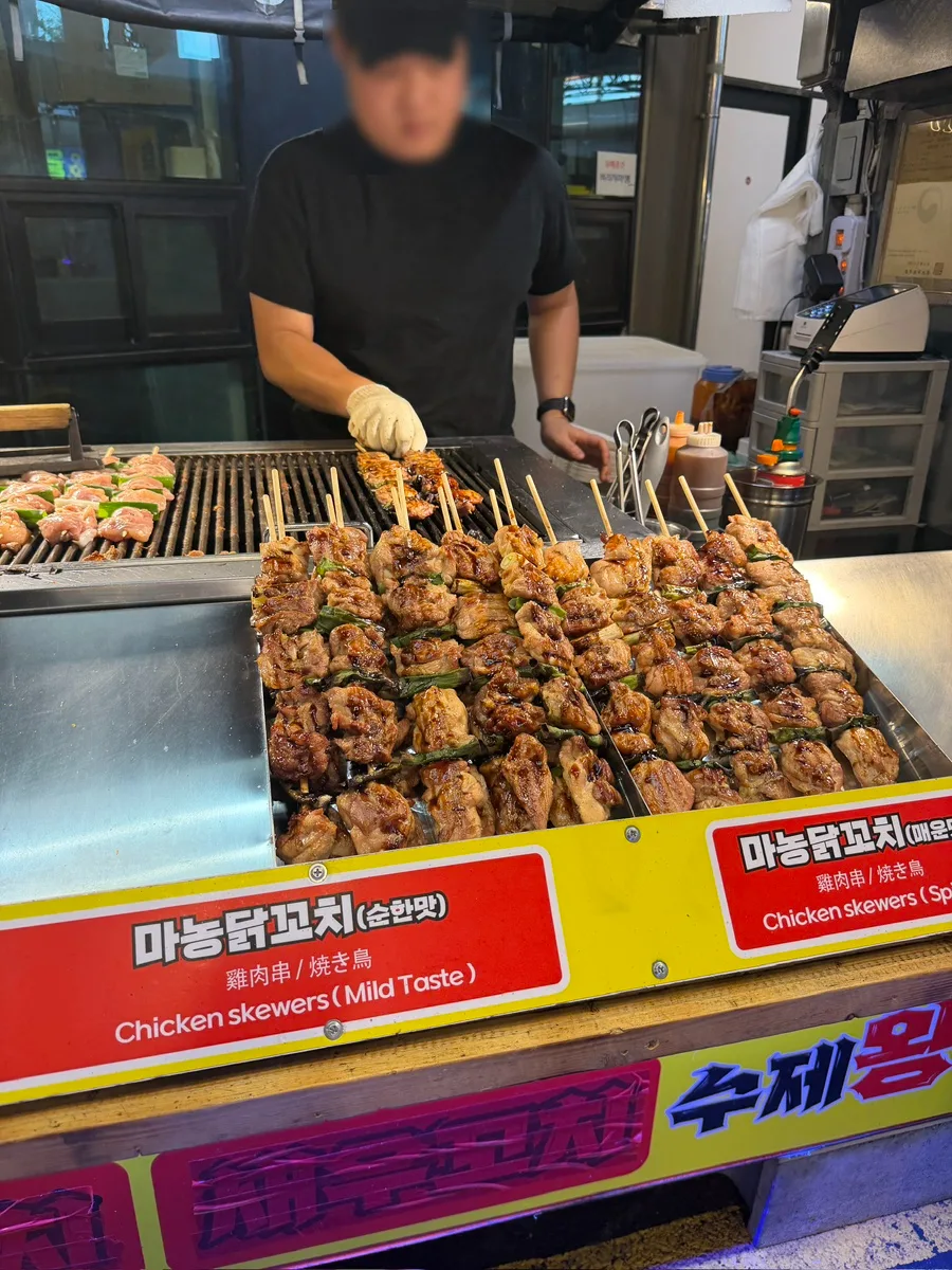 西帰浦毎日オルレ市場 — 鉄板に並ぶ鶏肉の串焼き