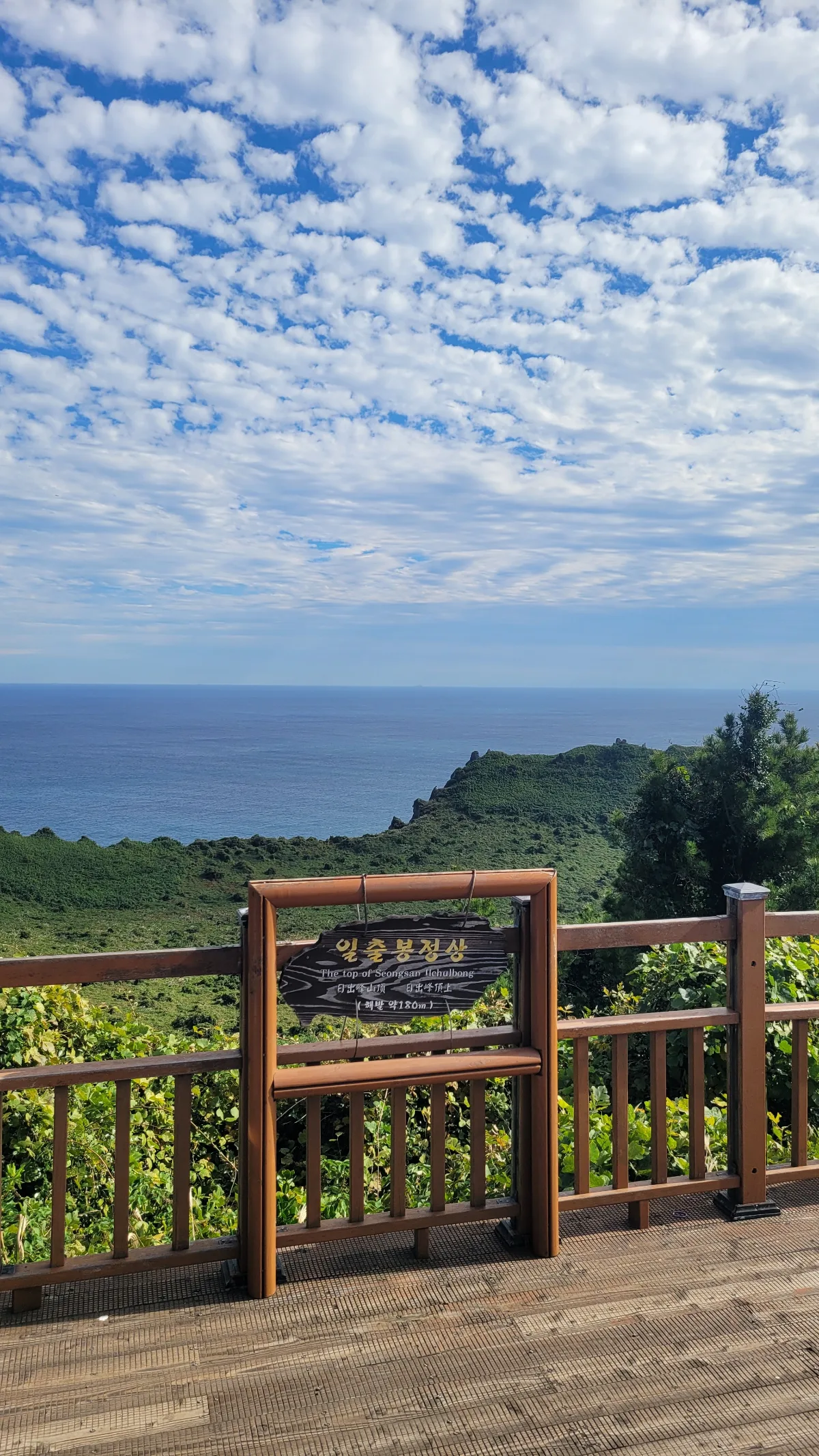 山頂標識越しの海と雲